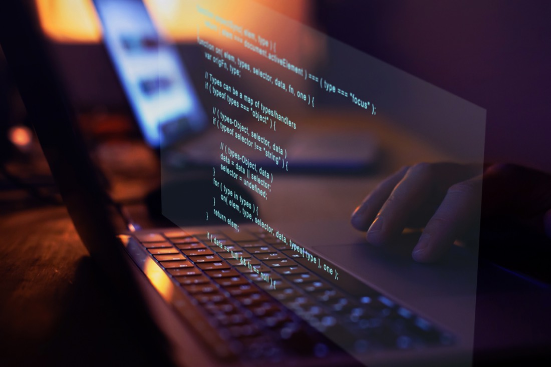 An MGNS developer writing code on a laptop with an overlaid program snippet